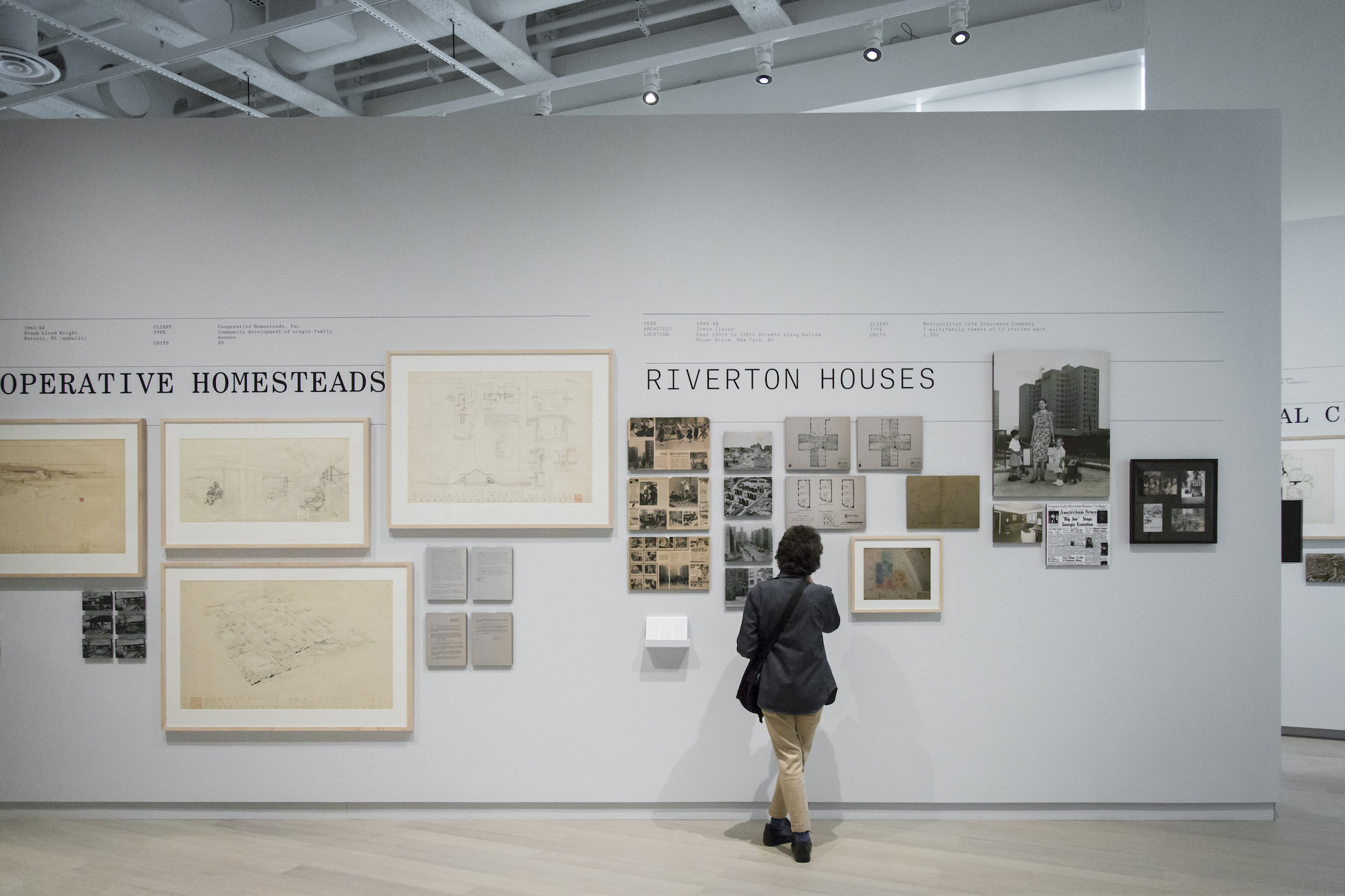 Woman standing in front of a gallery wall presenting FLW work.
