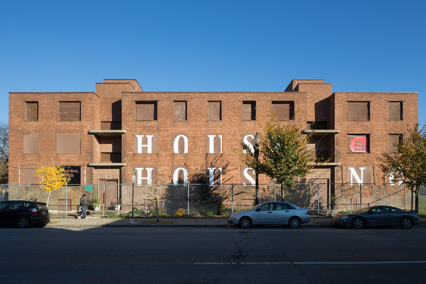 Photograph of brick building with House Housing Painted on the walls