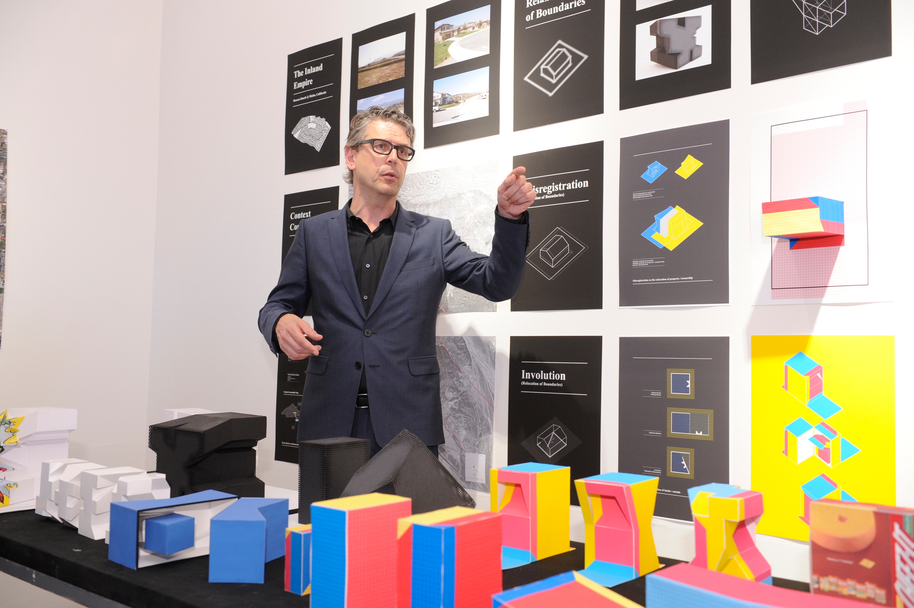 A man standing in front of a wall posted with drawings