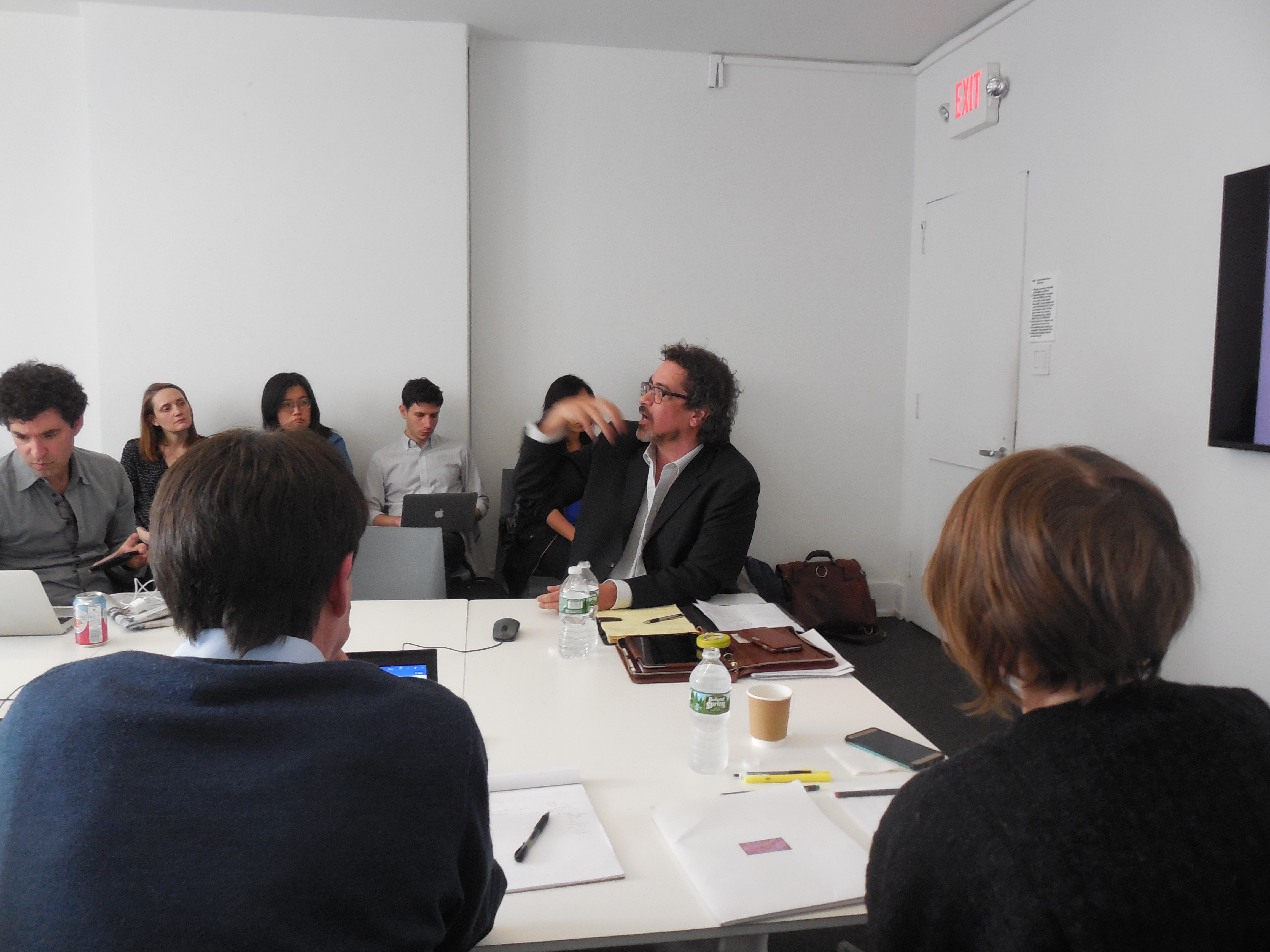 A man speaking to a group of people seated around a conference table