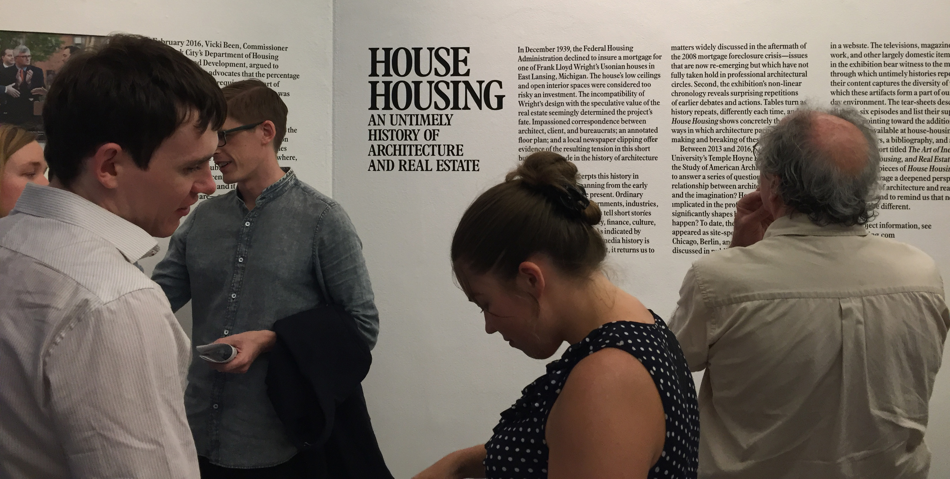 People standing in front of text of an exhibition