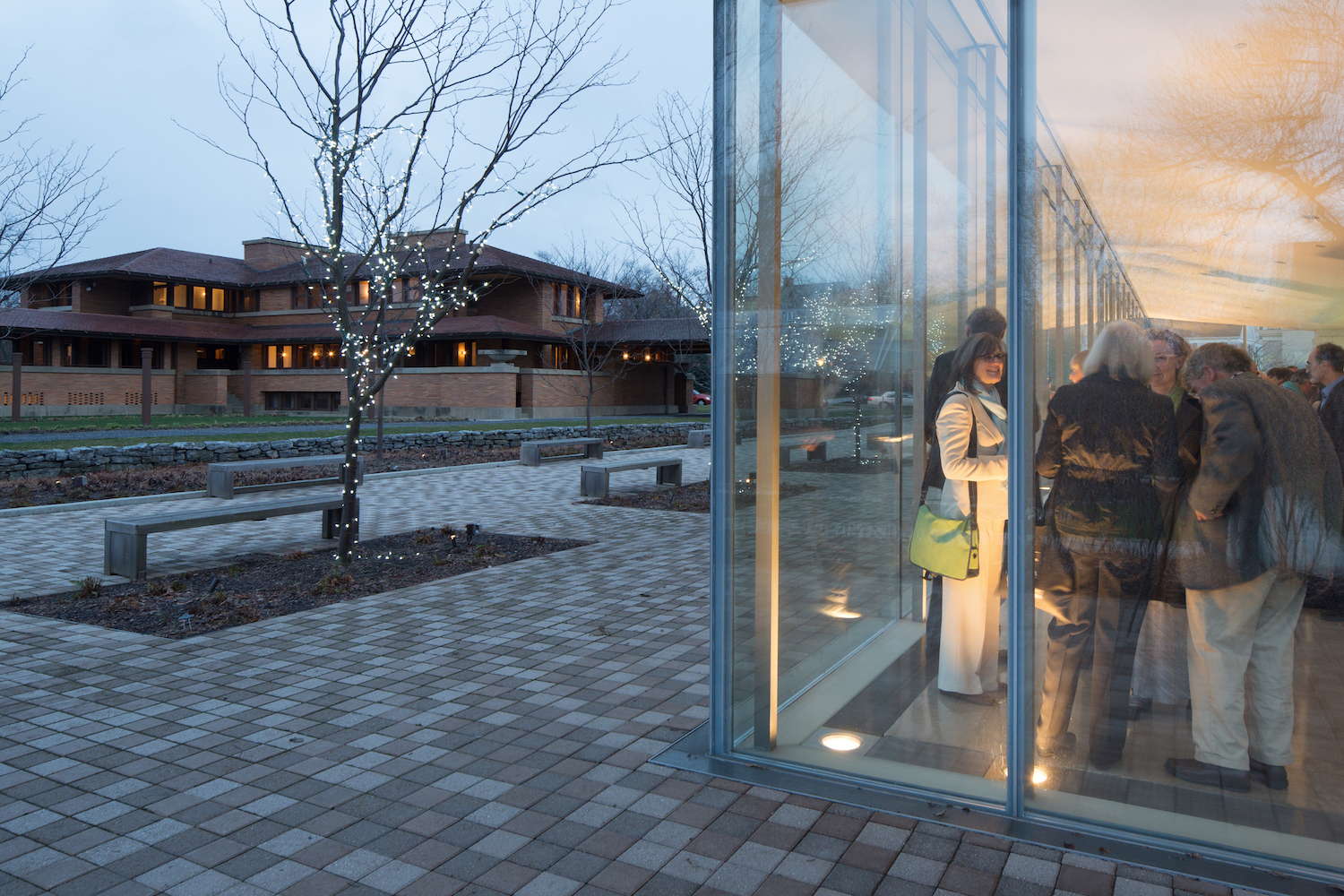 Photograph of exterior and see a crowd of people inside through transparent glass
