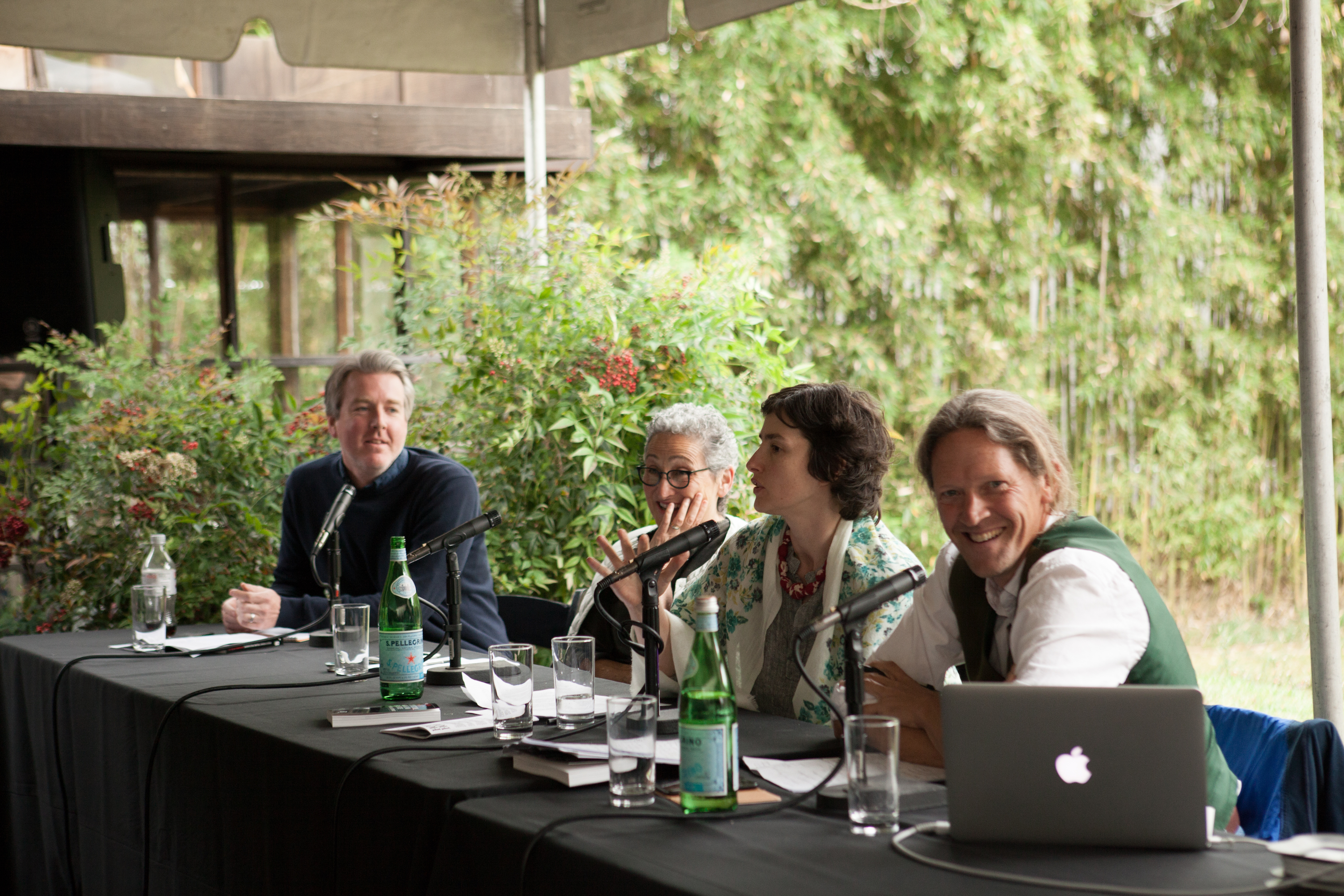 Panel of speakers sitting at a long table outside