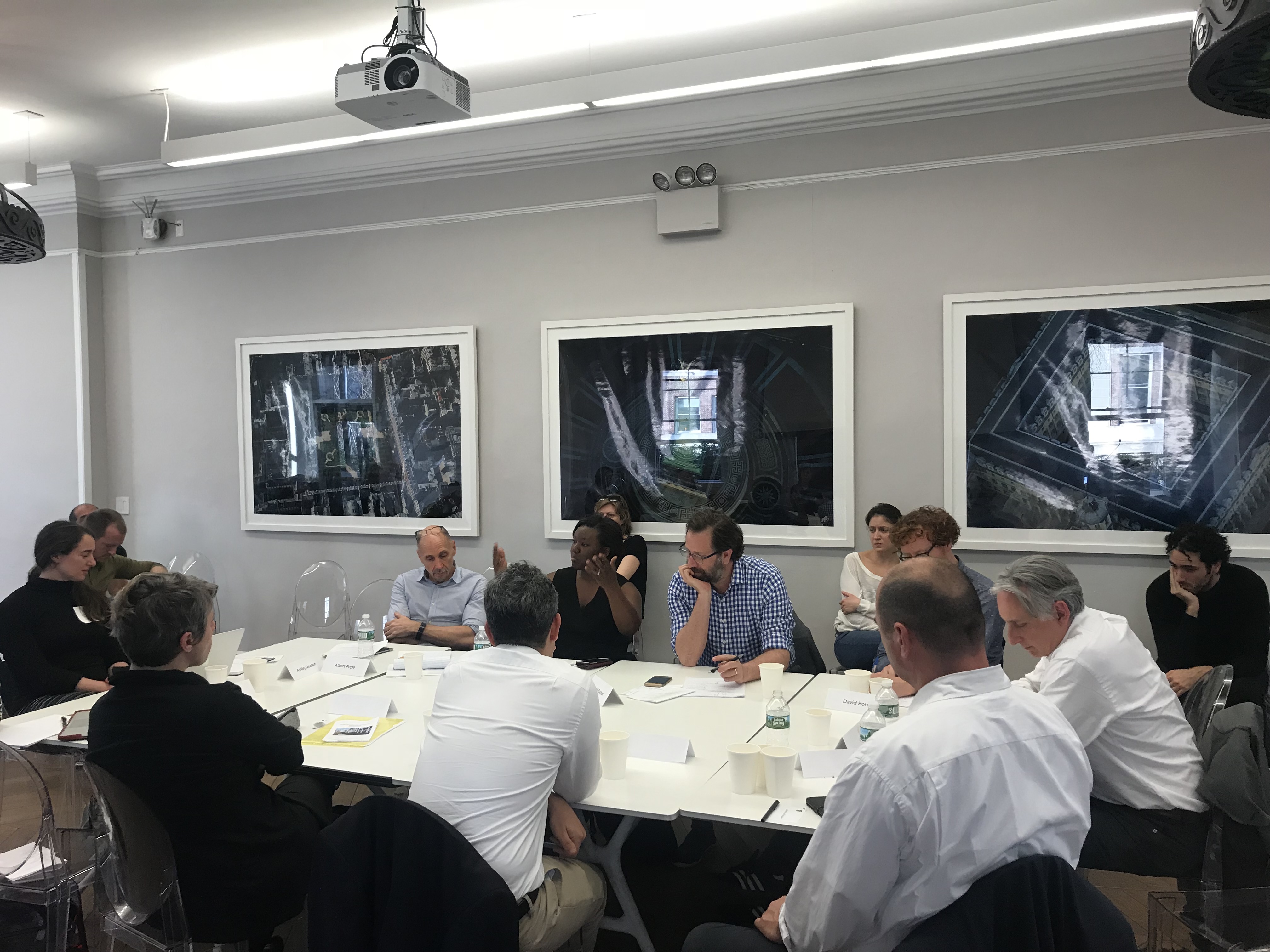 A group of fourteen people gathered in discussion around a seminar table