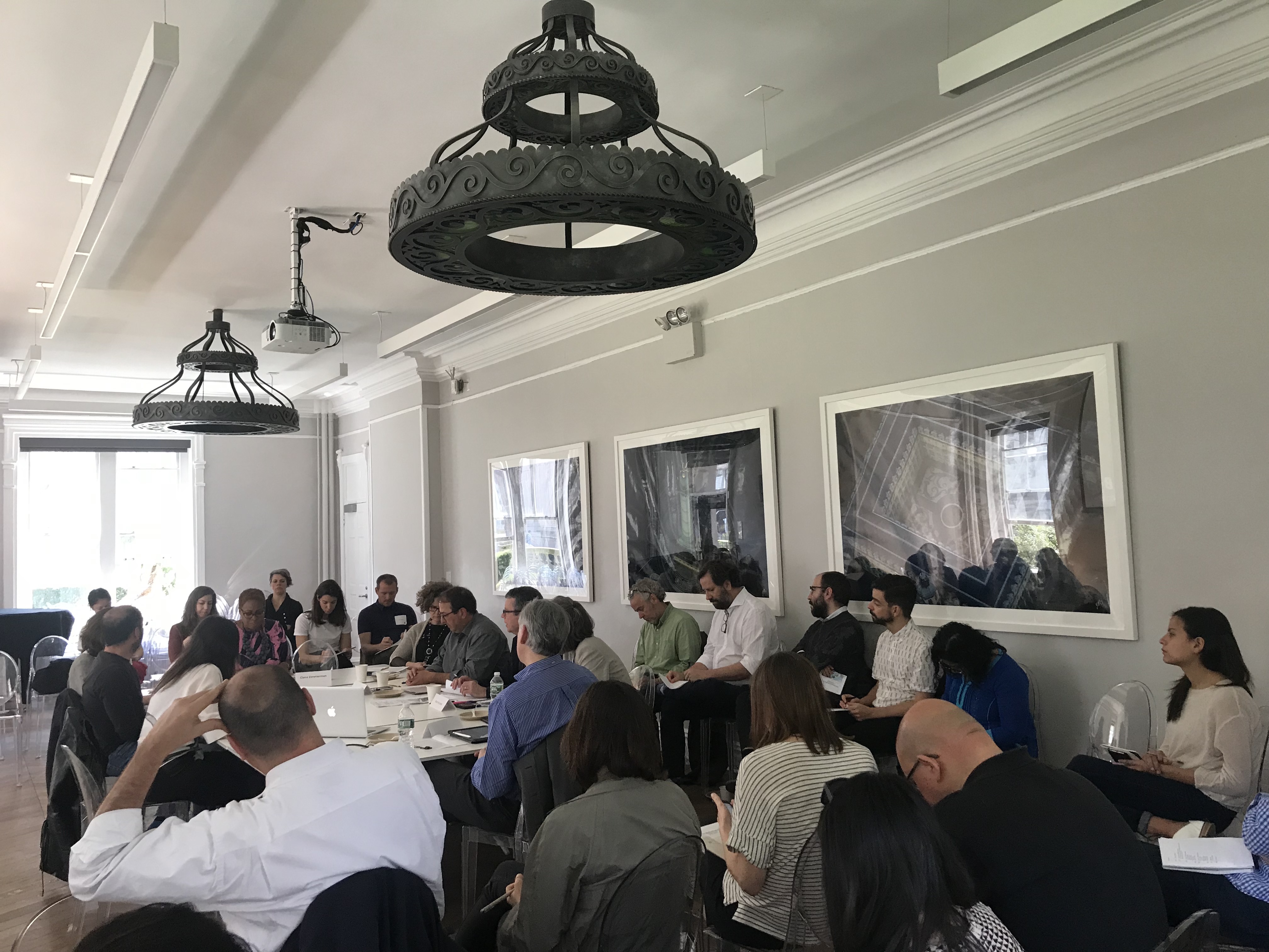 A group of twenty people gathered in a small seminar room around a table