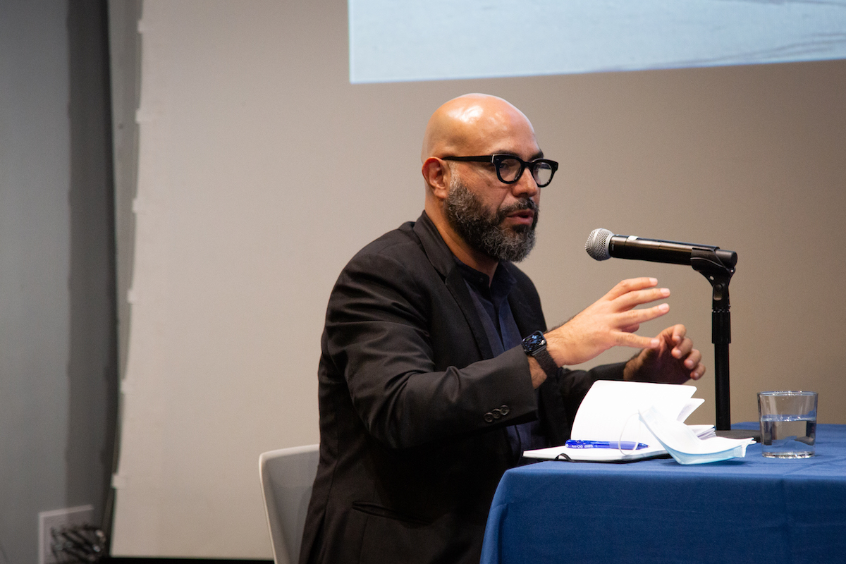 Quilian Riano sitting at the table moderating the discussion